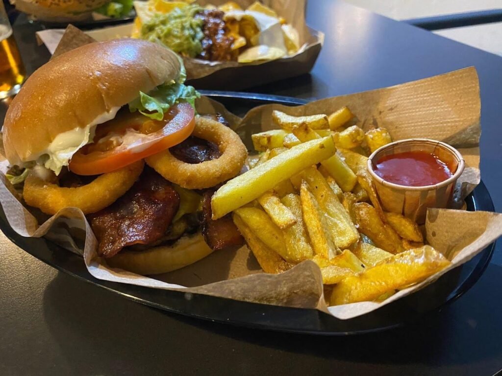 Hamburguesa con aros de cebolla, tomate y patatas naturales en Why Not